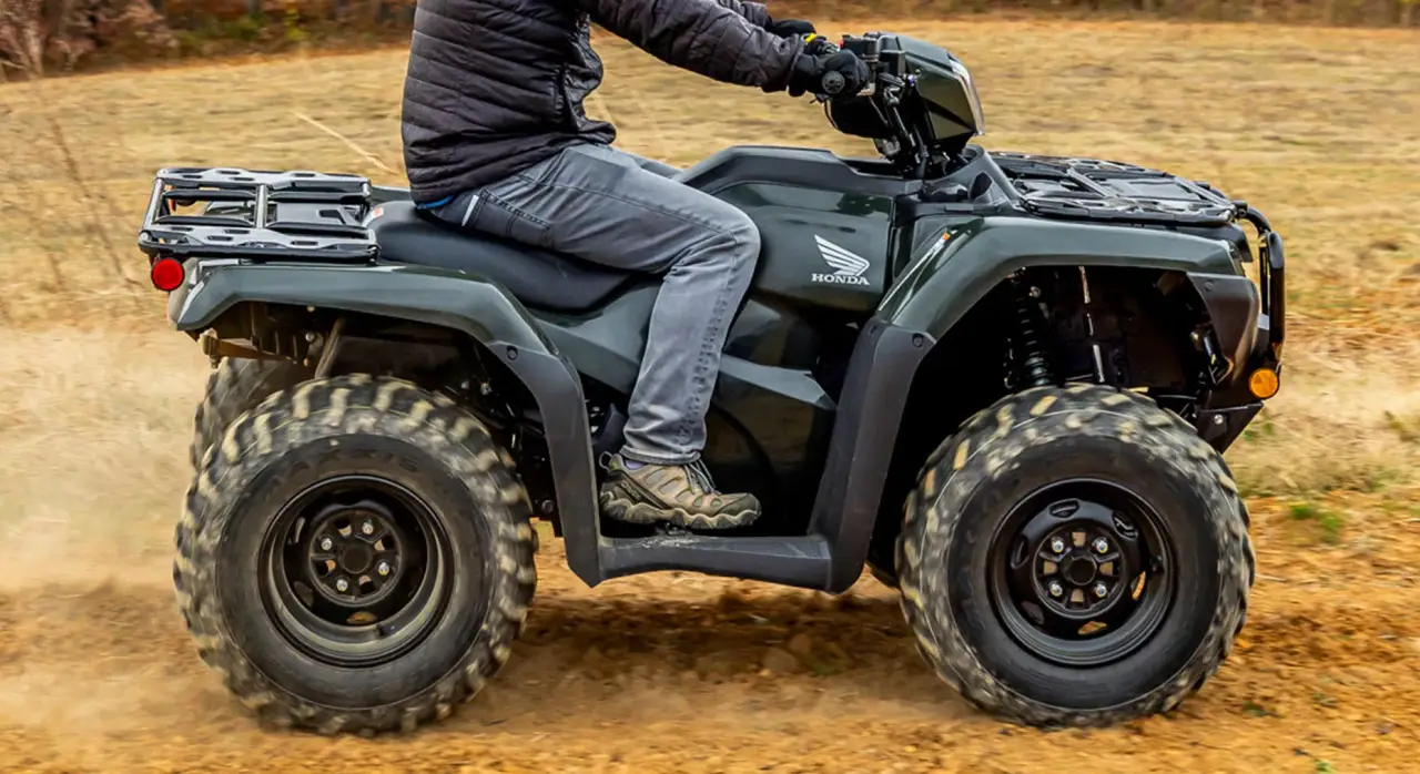 Utility quad accelerating across dry terrain